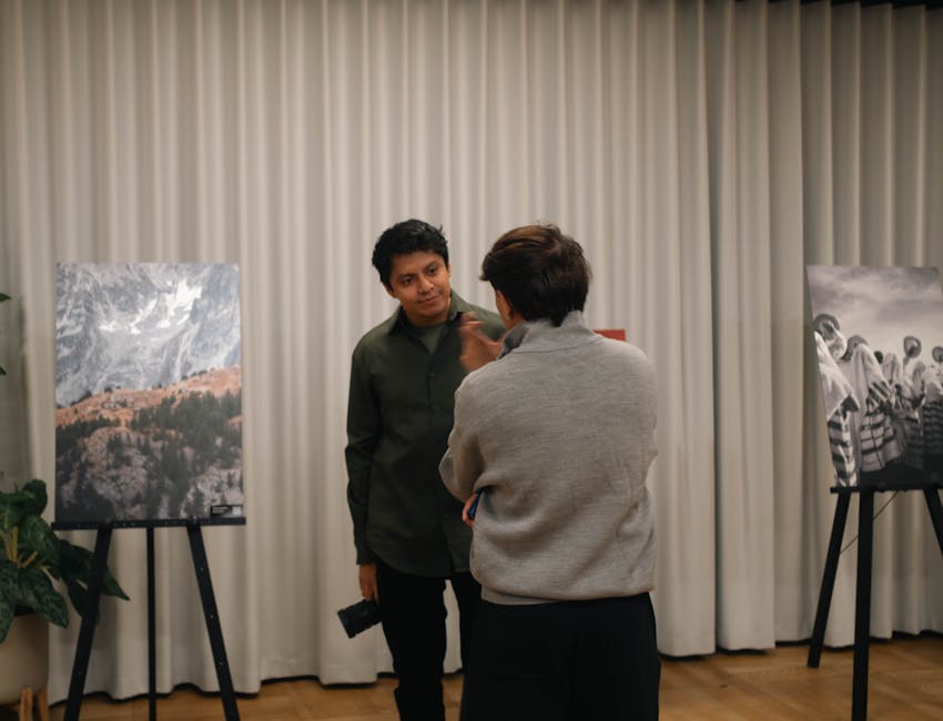 Two people engaged in conversation at an art gallery with photo exhibits.